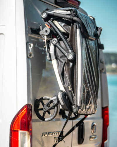 Folded kids bike trailer mounted on the PUSHrack on the rear of a campervan