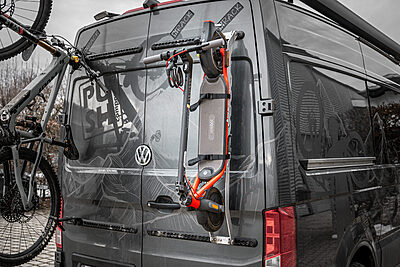 E-scooters on the PUSHrack e-scooter rack on airline rails next to the mounted PUSHrack bike rack on the campervan.