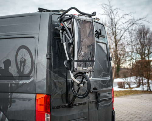 Folded kids bike trailer mounted on the PUSHrack on the rear of a campervan