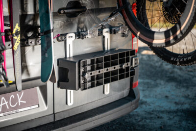 PUSHrack leveling wedges mounted sideways on the PUSHrack Room Extender attached to airline rails at the rear of a camper van