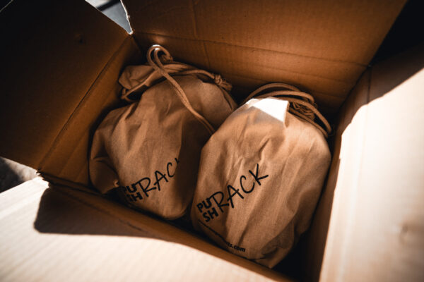 Sustainable PUSHrack packaging using reusable fabric bags inside a shipping box
