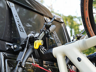 Mountainbike am PUSHrack System befestigt, mit Lenkerhalter und Reifenhalter auf einer Airlineschiene am Heck eines Campervans – sichere und stabile Fixierung von PUSHcomponents.