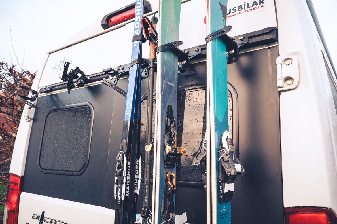 Campervan in Schweden transportiert zwei Paar Ski und ein Paar Langlaufski.