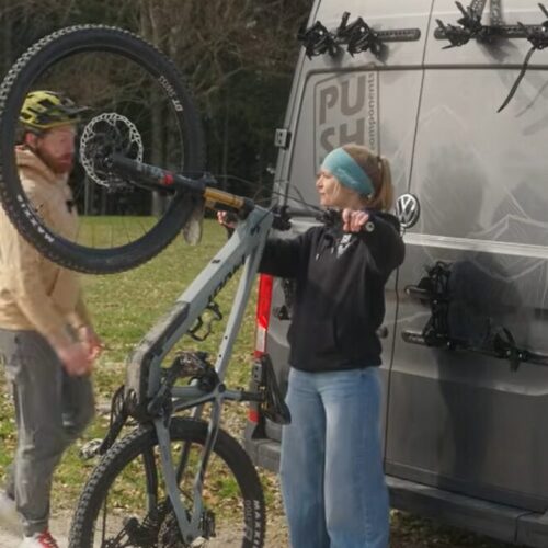 Lici positioniert sich mit dem Fahrrad vor dem Bus um das Fahrrad in der V3 einzuhängen